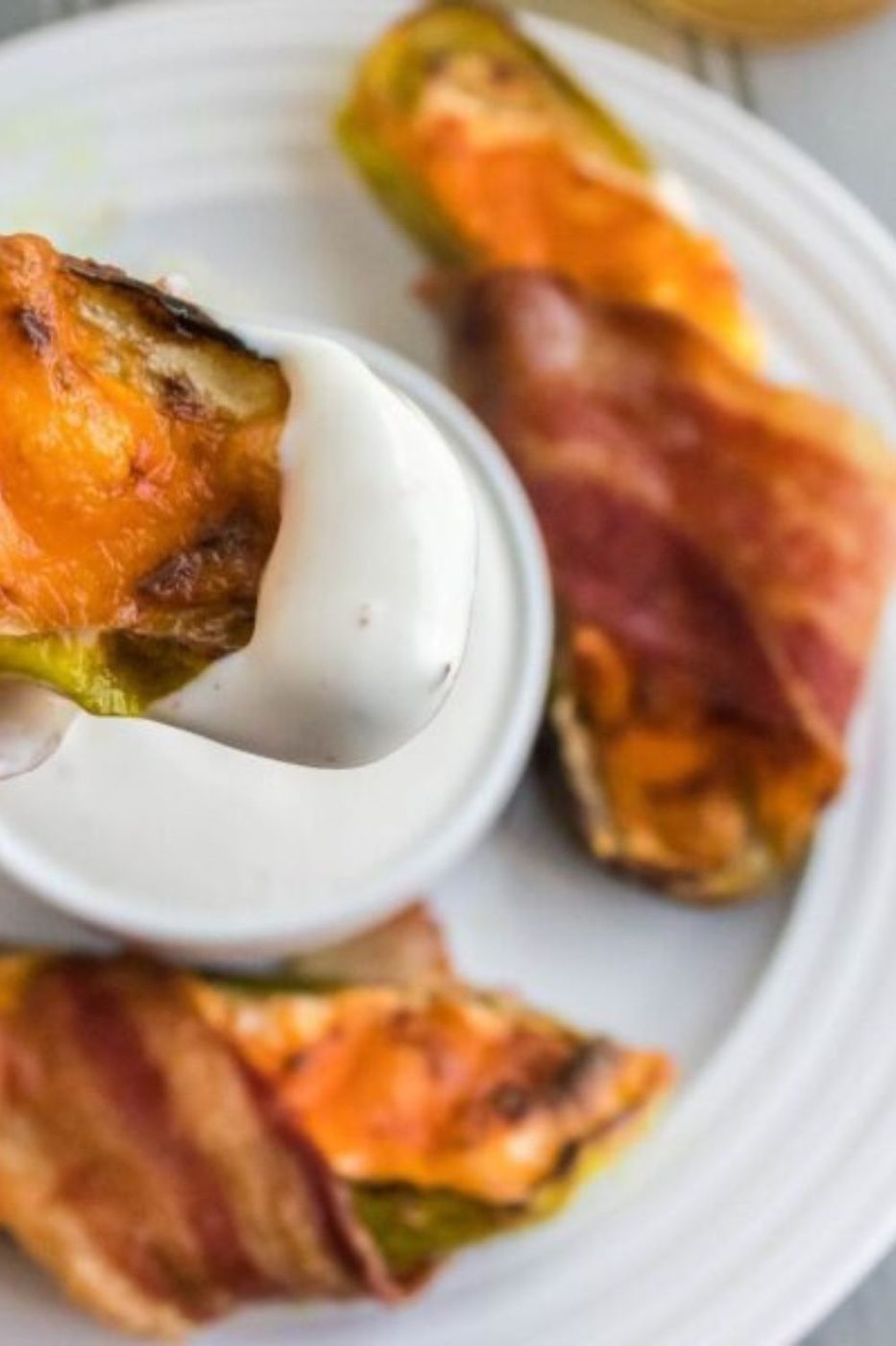 plate full of bacon wrapped pickles with one being dipped into a sauce