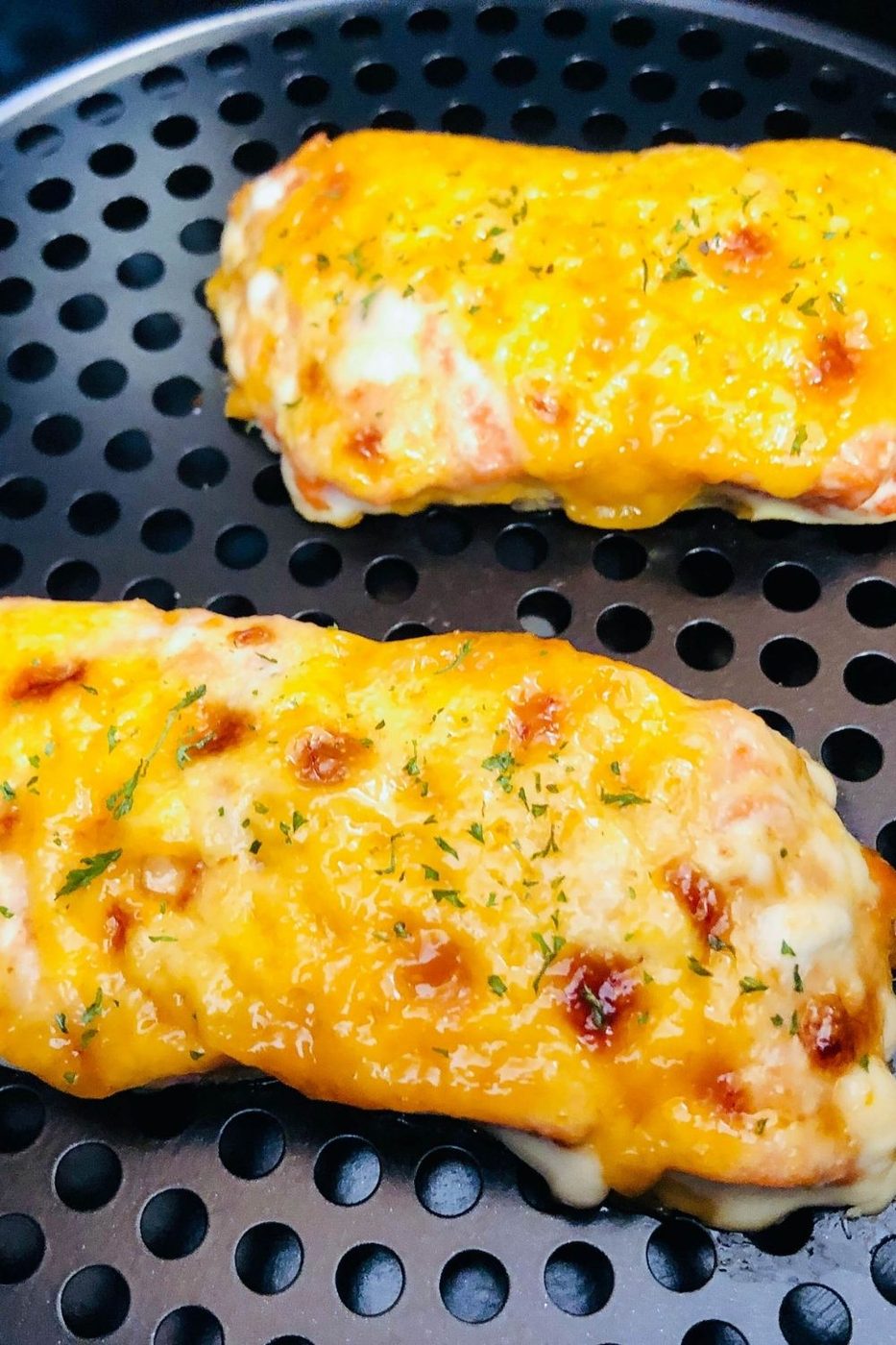 salmon cooked in an air fryer basket with bang bang sauce on top 