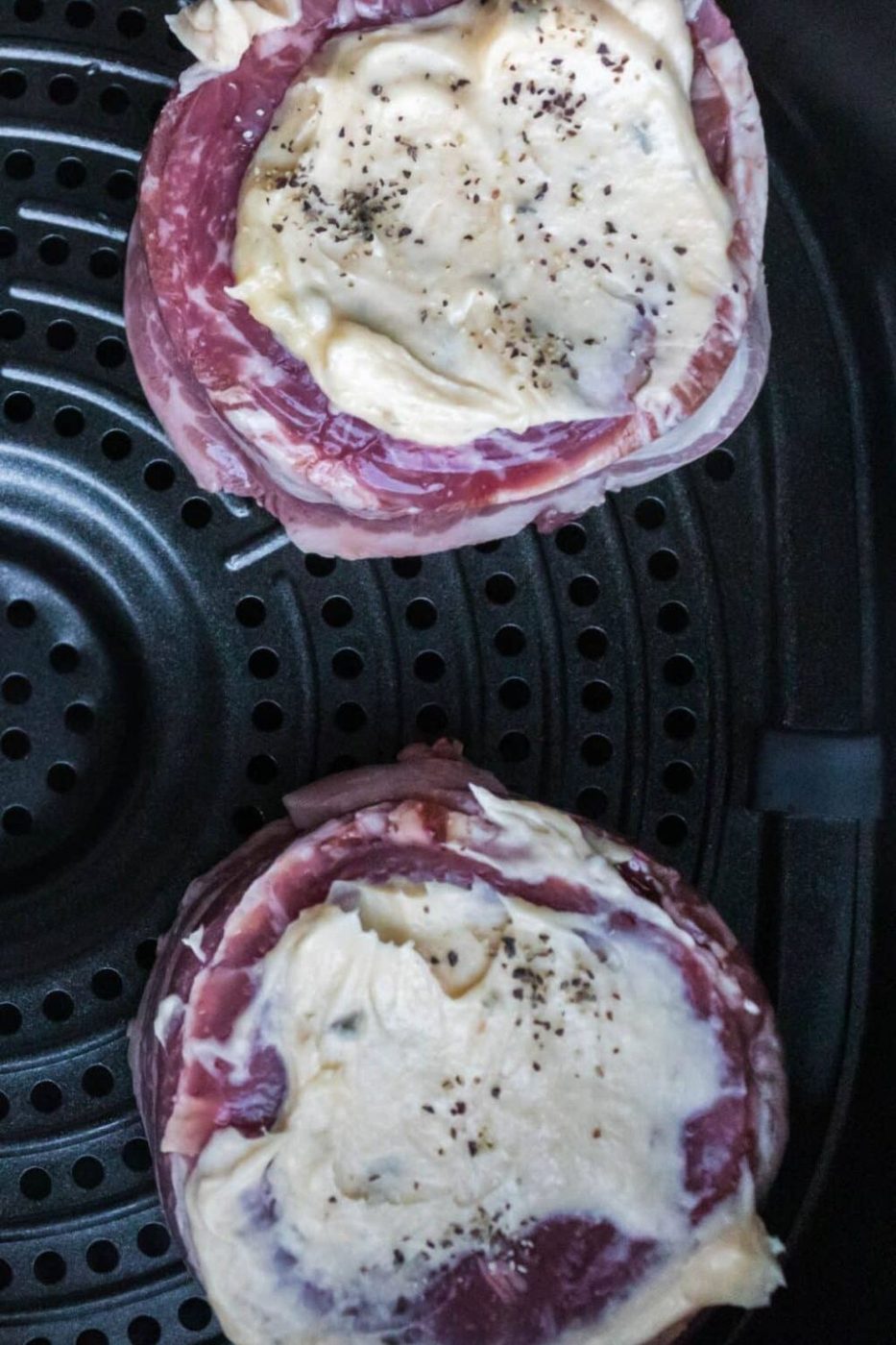 Air Fryer Filet Mignon in an air fryer with butter spread on the top 