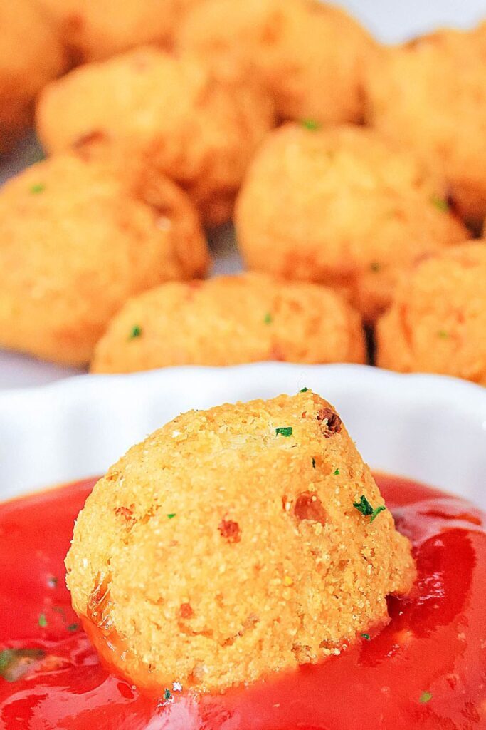ketchup in a bowl with a homemade hush puppy dipped in it 