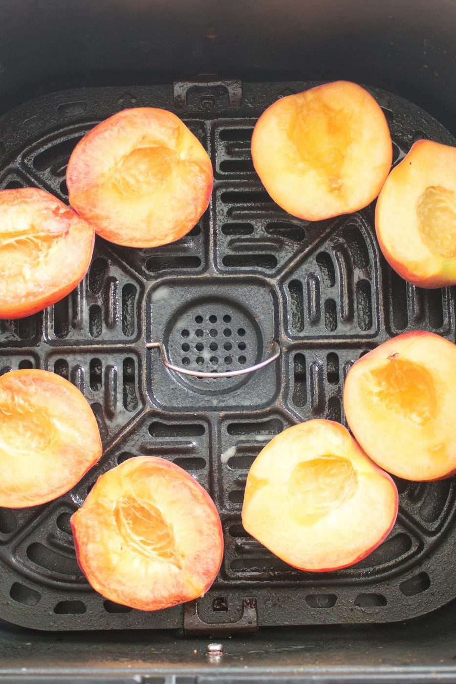 fresh Air Fryer Peaches spread out in the air fryer basket before they are cooked