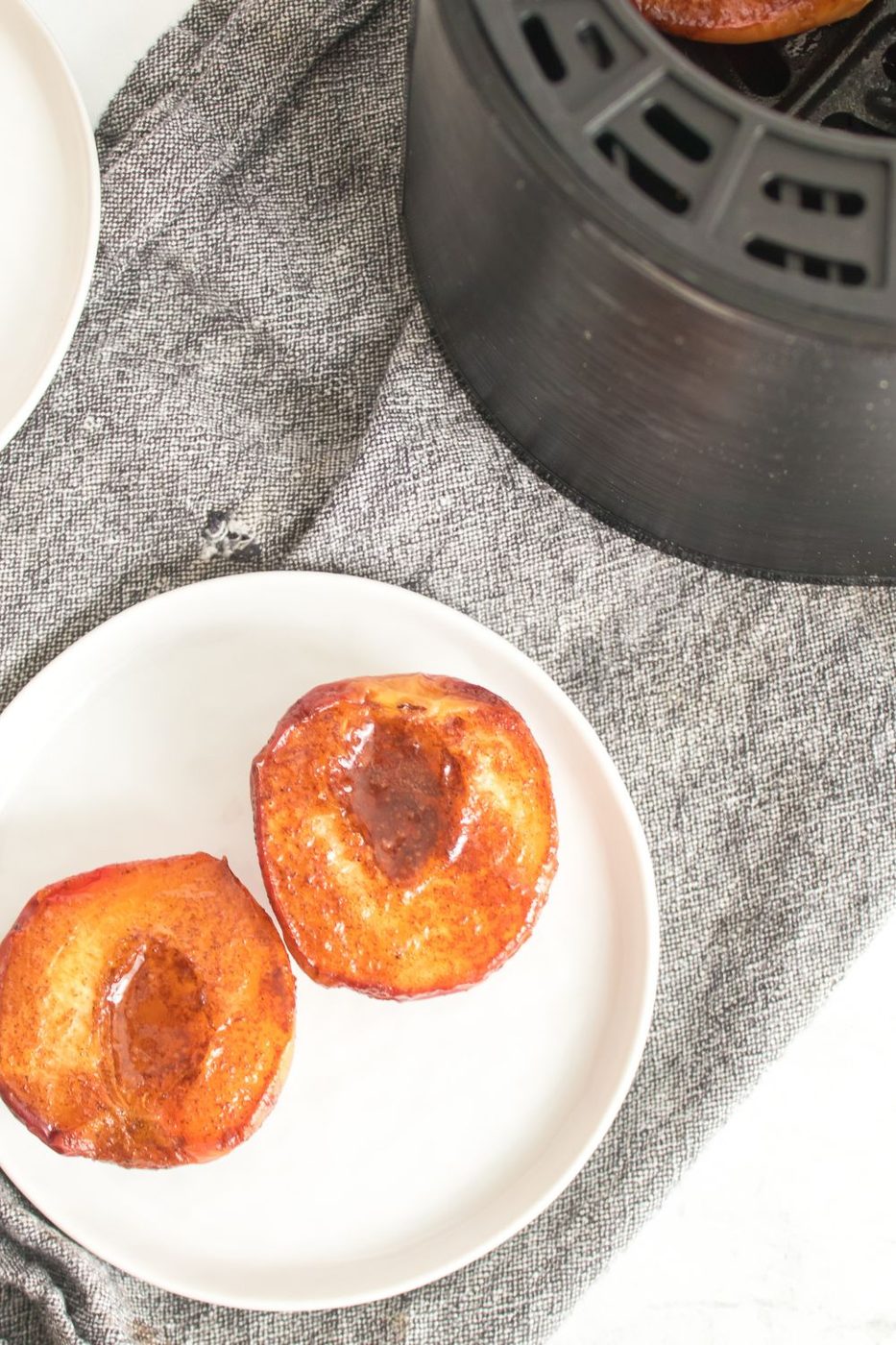grilled Air Fryer Peaches on plate with air fryer behind it on table