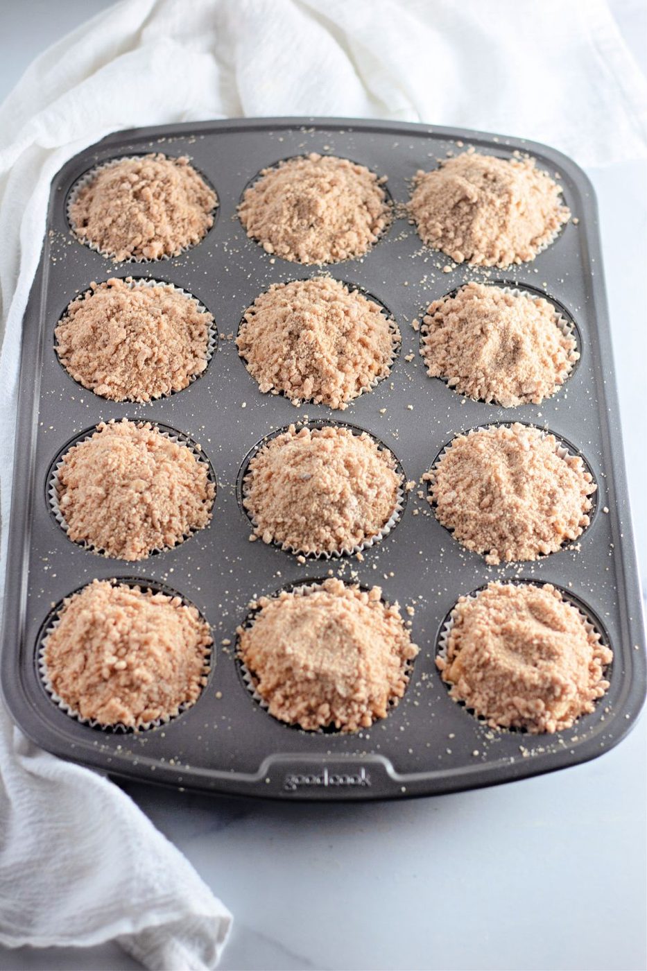 crumble topped muffins in a muffin tin on table