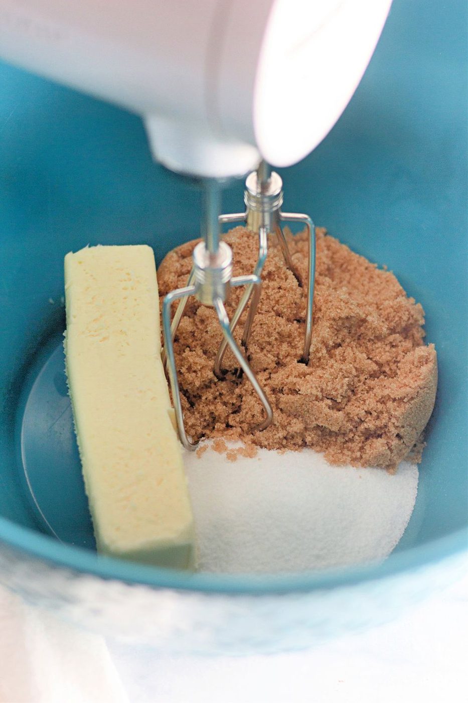 hand mixer in a bowl with sugars and butter in bowl