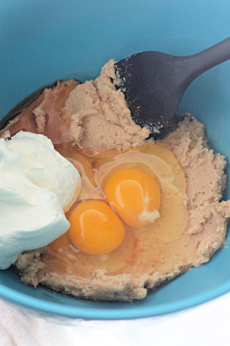 eggs and sour cream with spatula in a bowl on table