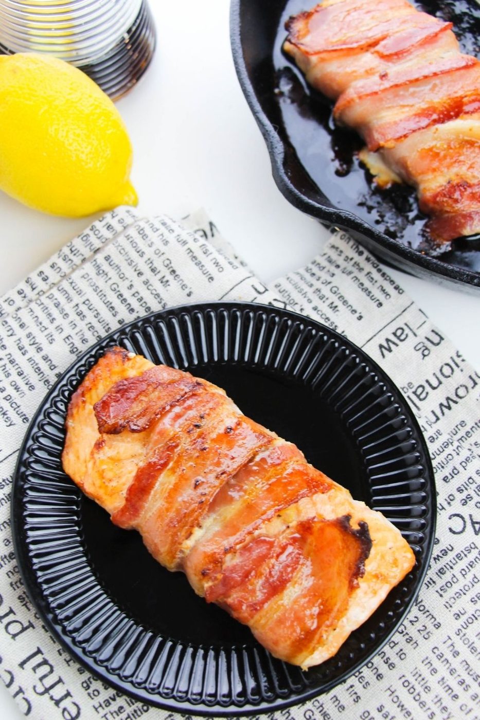 maple bacon salmon on black plate with lemon behind it