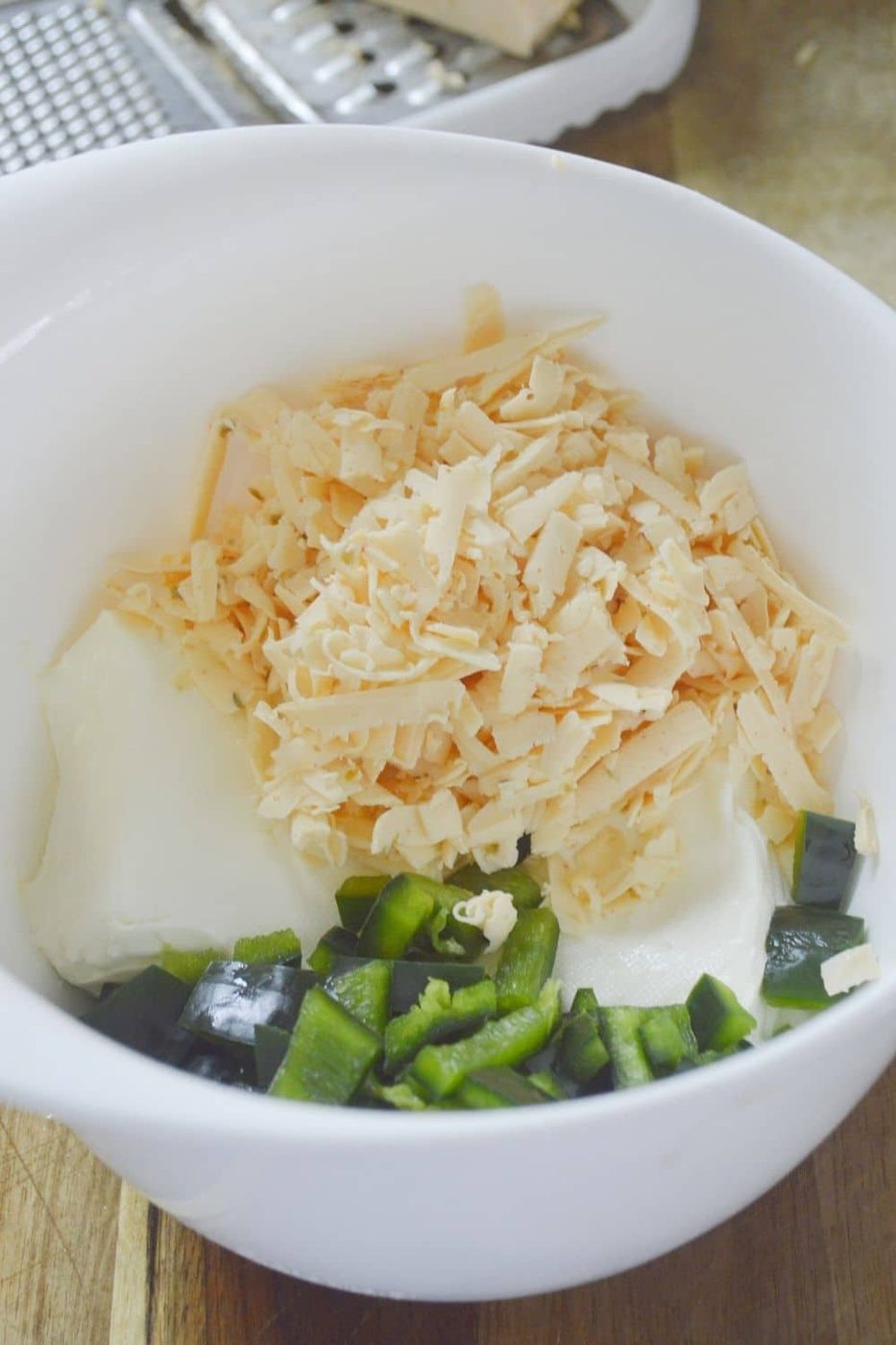 shredded cheese, cream cheese and peppers in bowl