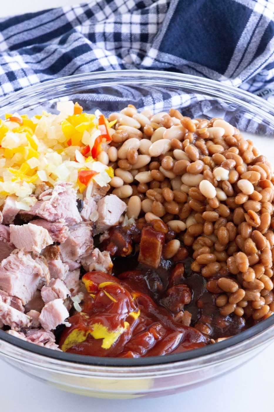 ingredients for beans in a glass bowl with towel behind it