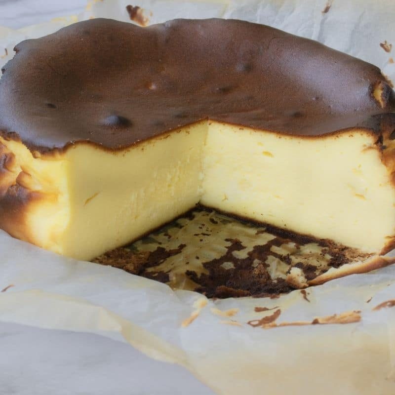 sliced burnt cheesecake with parchment paper around it 