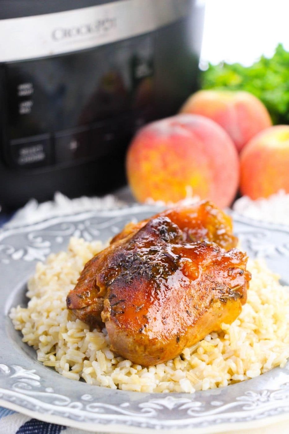 plate with rice and chicken on top and crockpot and peaches in background