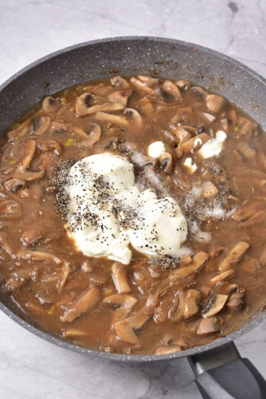 process of making Beef Stroganoff in a skillet that has meat mixture with sour cream in the center and seasonings 