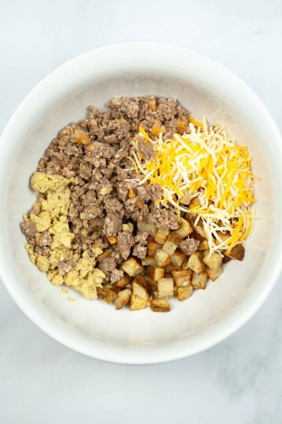 white bowl full of sausage, cheese, eggs, potatoes, for making Breakfast Chimichangas 