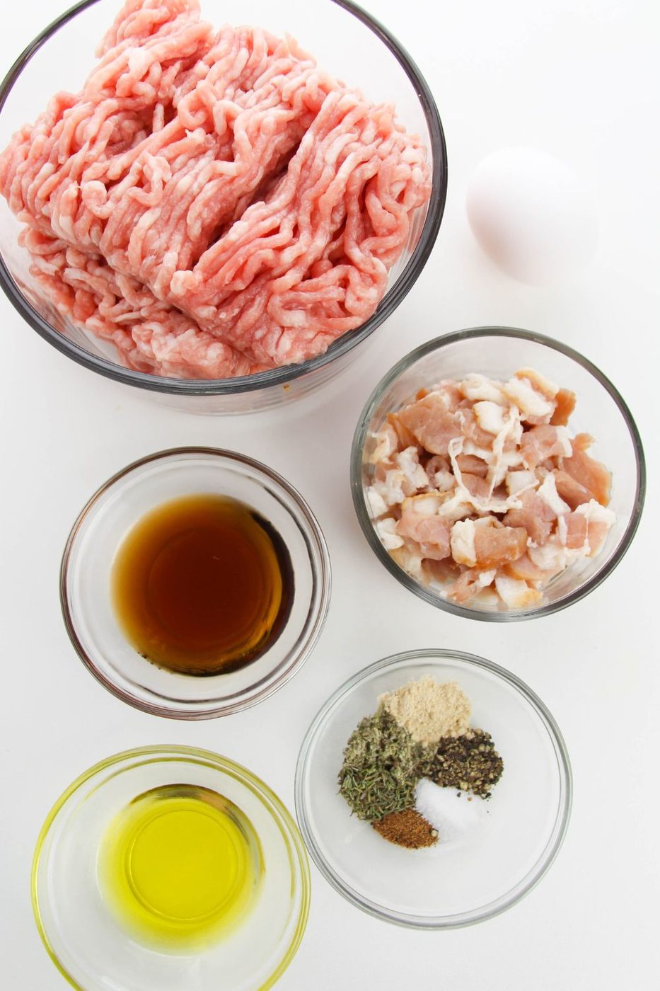 ingredients for sausage in glass bowls on white table