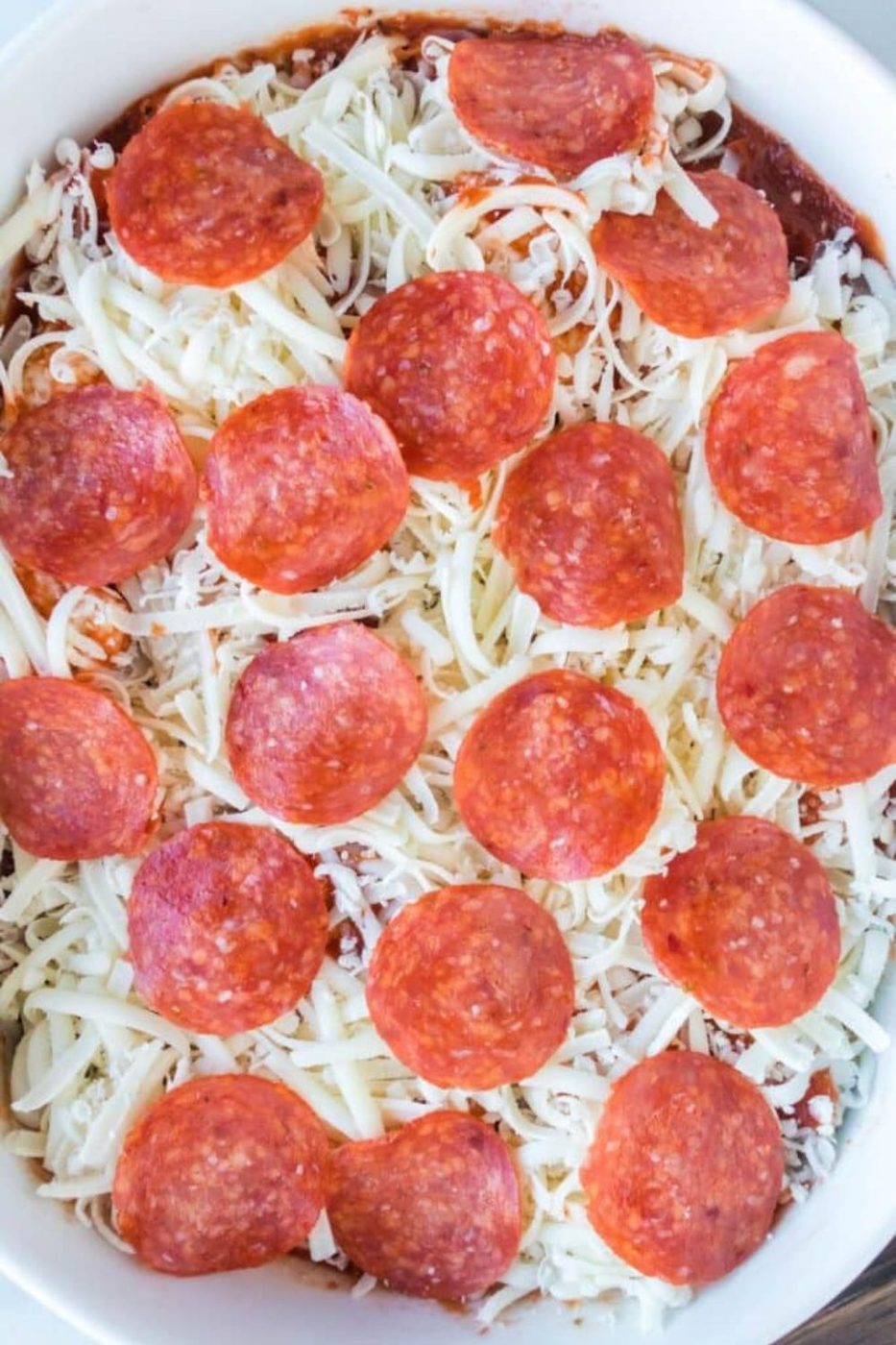 raw bubble bread pizza in a casserole pan topped with pepperoni slices 