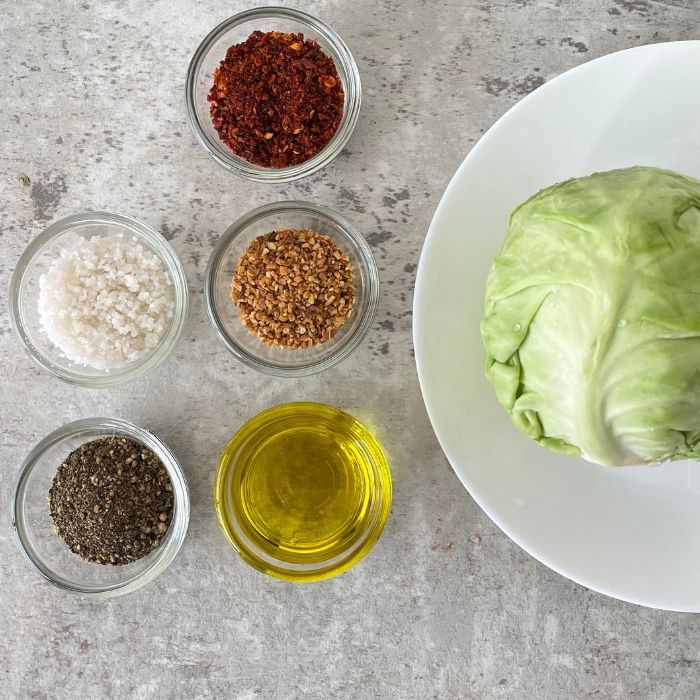 cabbage on a plate and spices in single bowls on a marble counter 