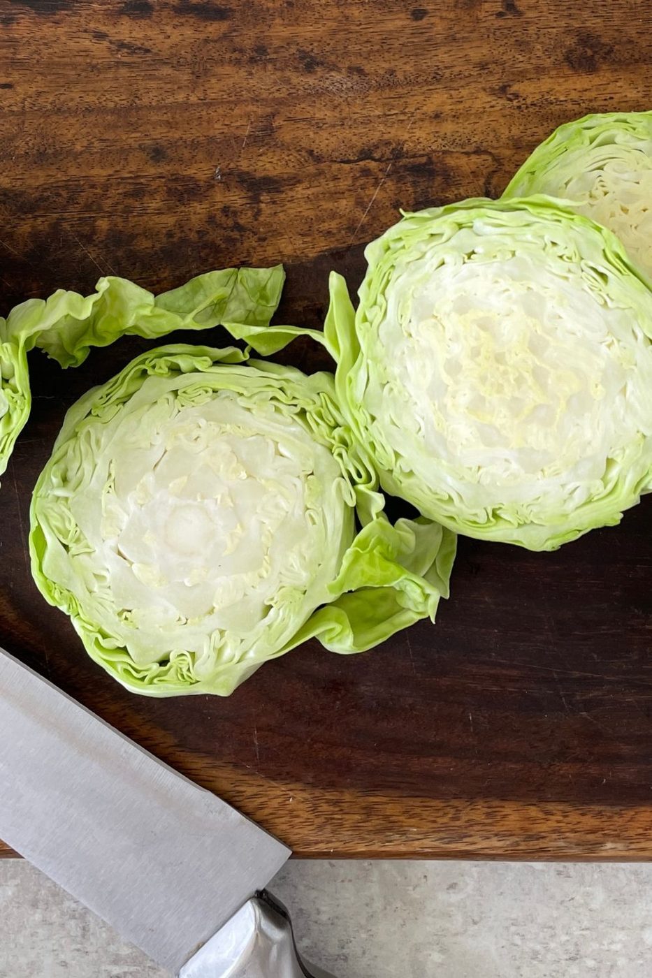 sliced cabbage steaks on a wooden cutting board 