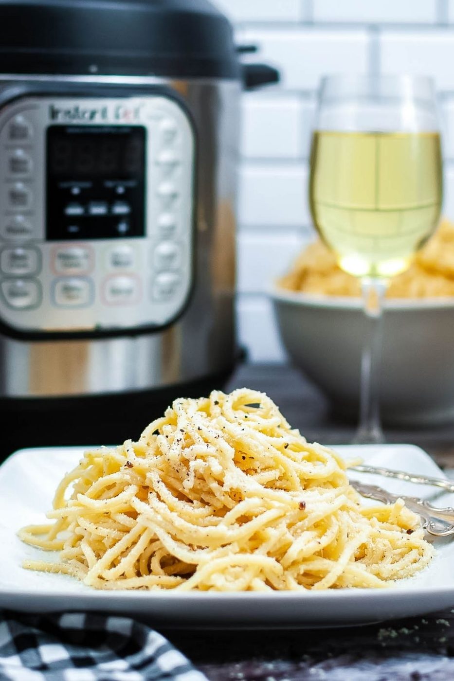 cacio pasta on a plate with wine behind it and instant pot