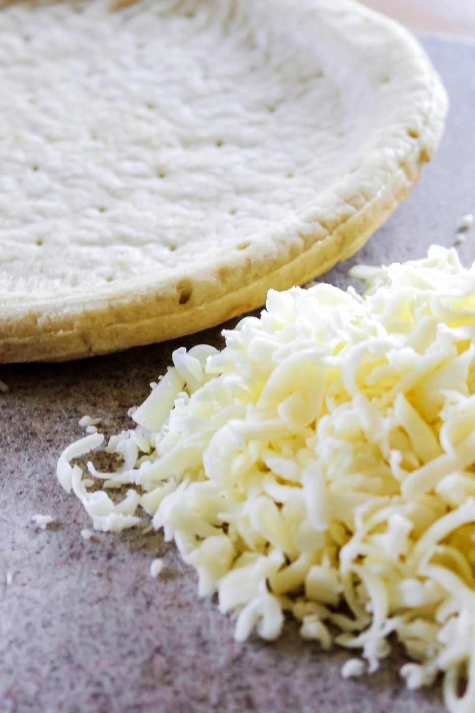 pizza crust and shredded cheese on table