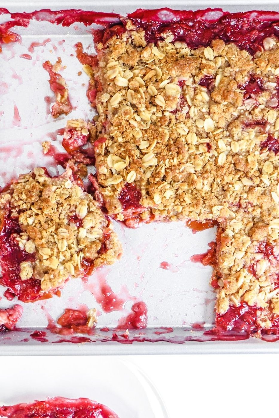 fruit crisp in the pan with pieces cut out of it 