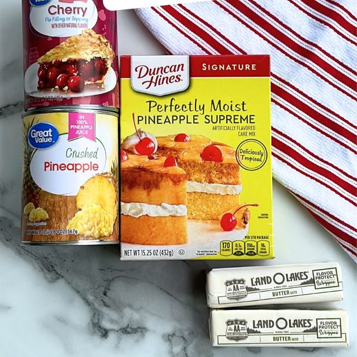 pie filling, pineapple, and cake mix and sticks of butter on table with towel behind it 
