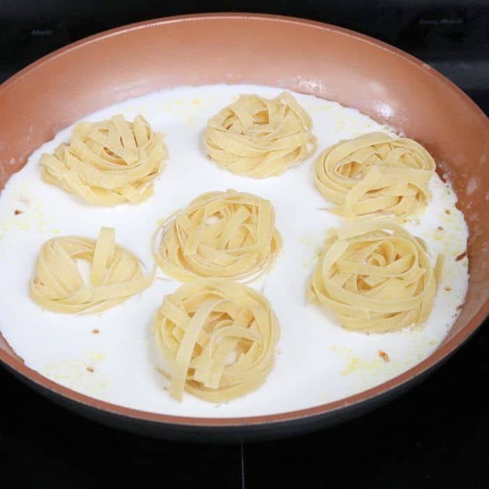 pot with cream sauce and nest of pasta noodles 