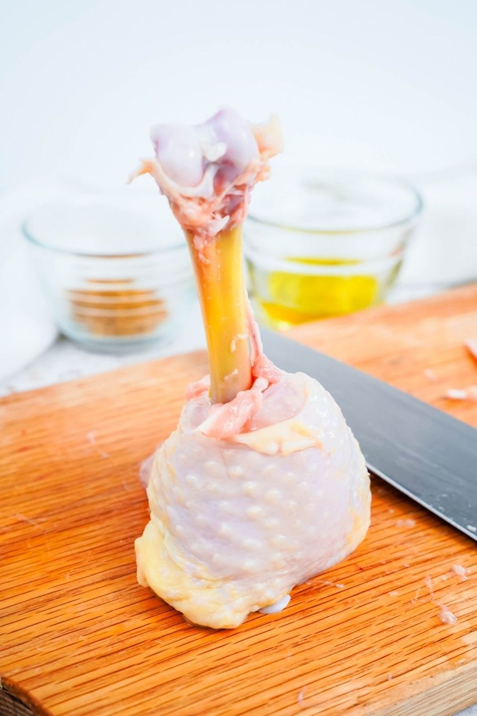 chicken leg lollipop on wooden cutting board with knife by it 