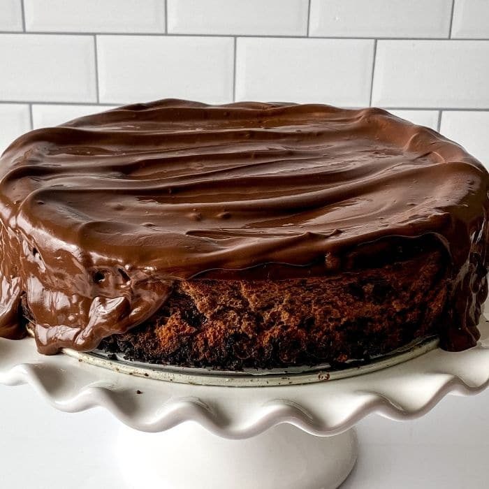 triple chocolate cheesecake on cake stand on counter 