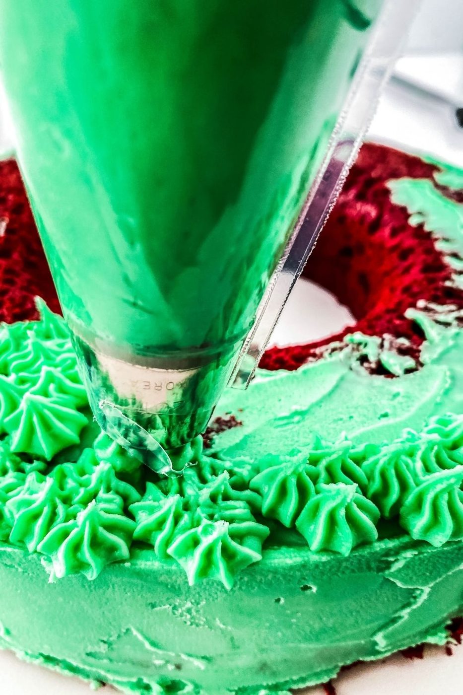 piping green frosting on cake