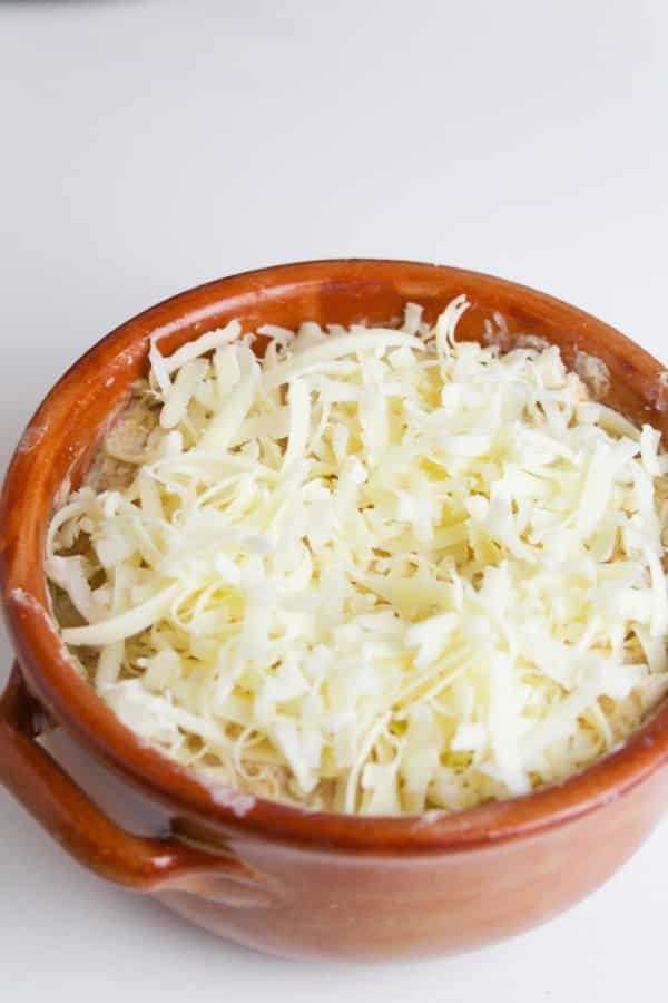 hot crab dip with shredded cheese on top of bowl 