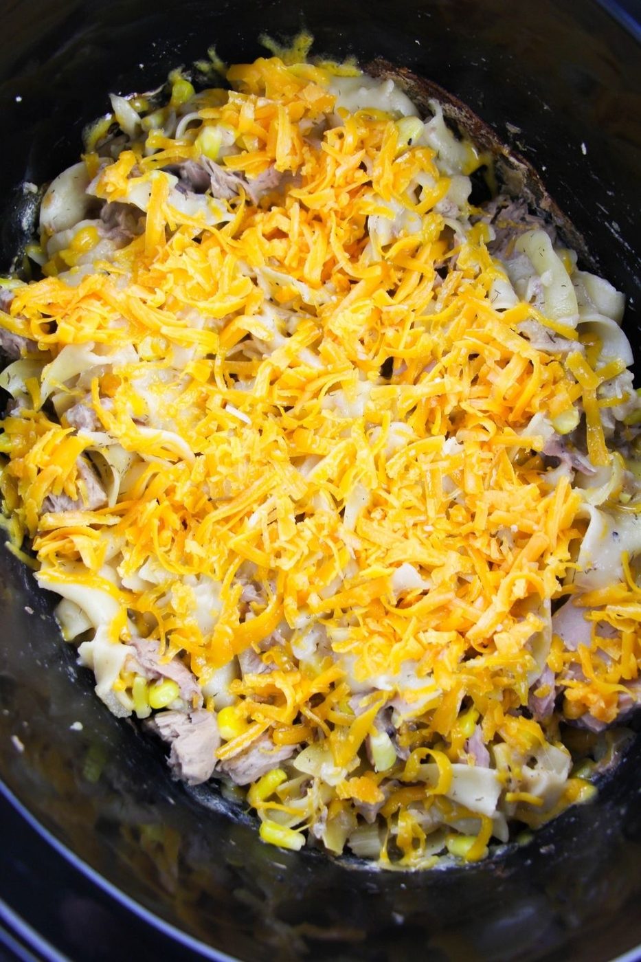 cheesy tuna noodles in crockpot with cheese on top