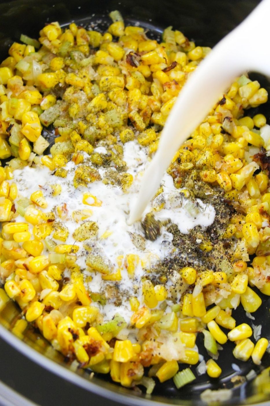 pouring milk in crockpot with corn and veggies inside