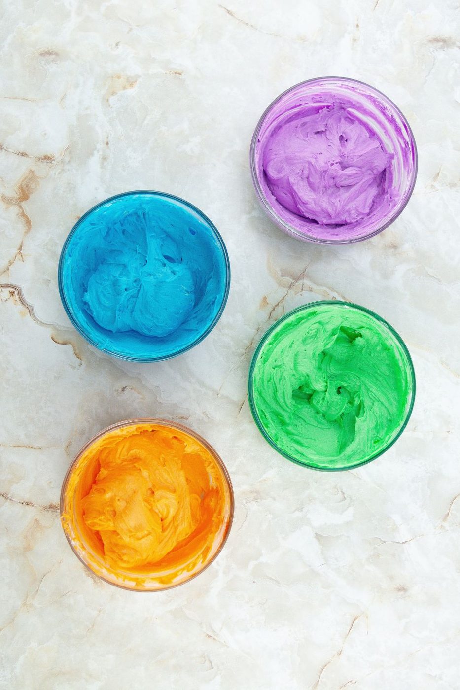 bright colored frosting in glass bowls 