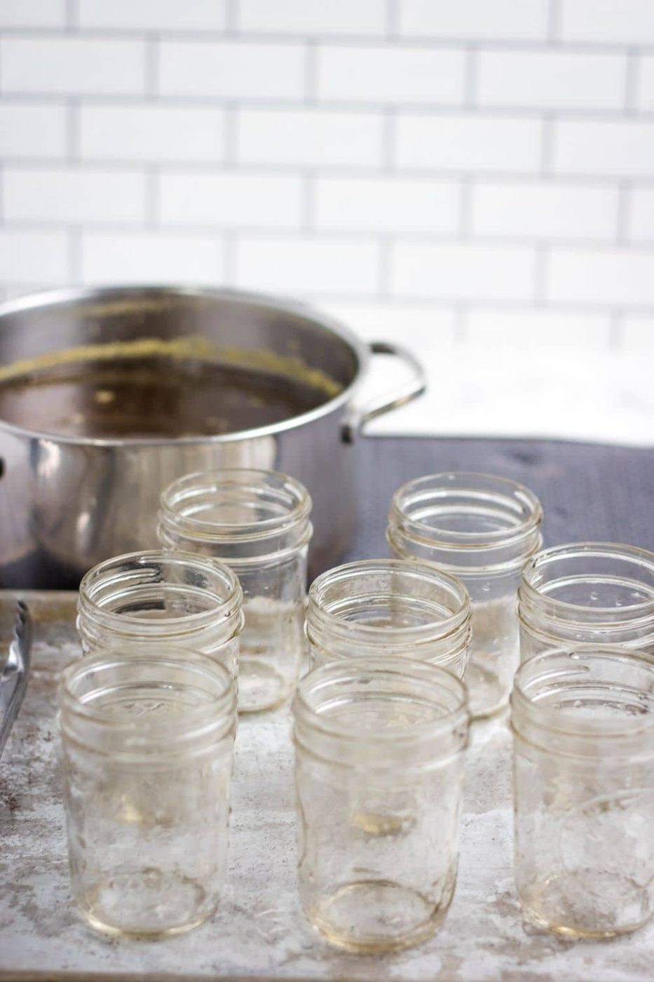 canning jar placed on table with pot of jelly behind it 