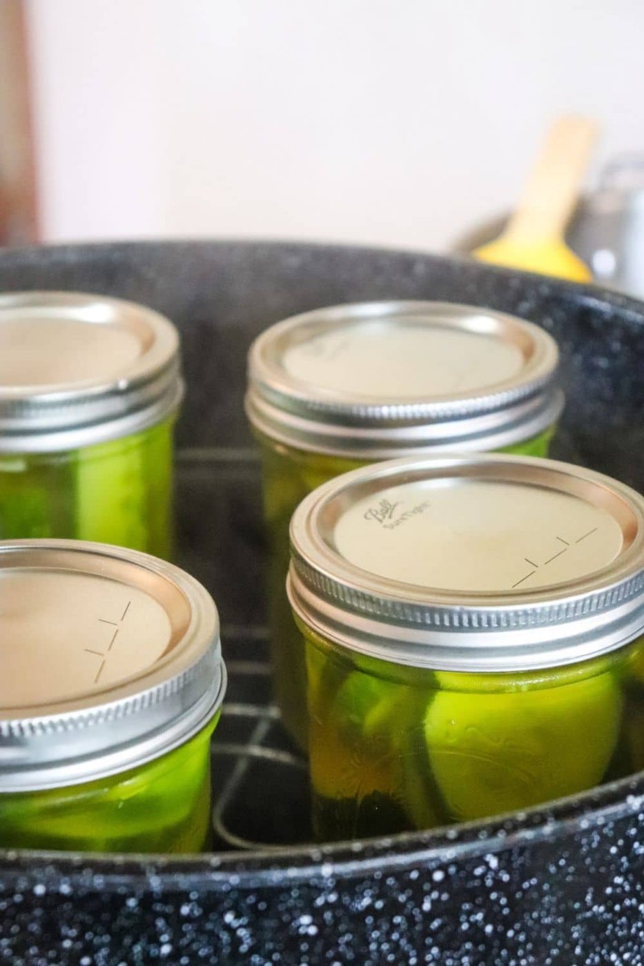 mason jars with cucumbers being canned in a canner