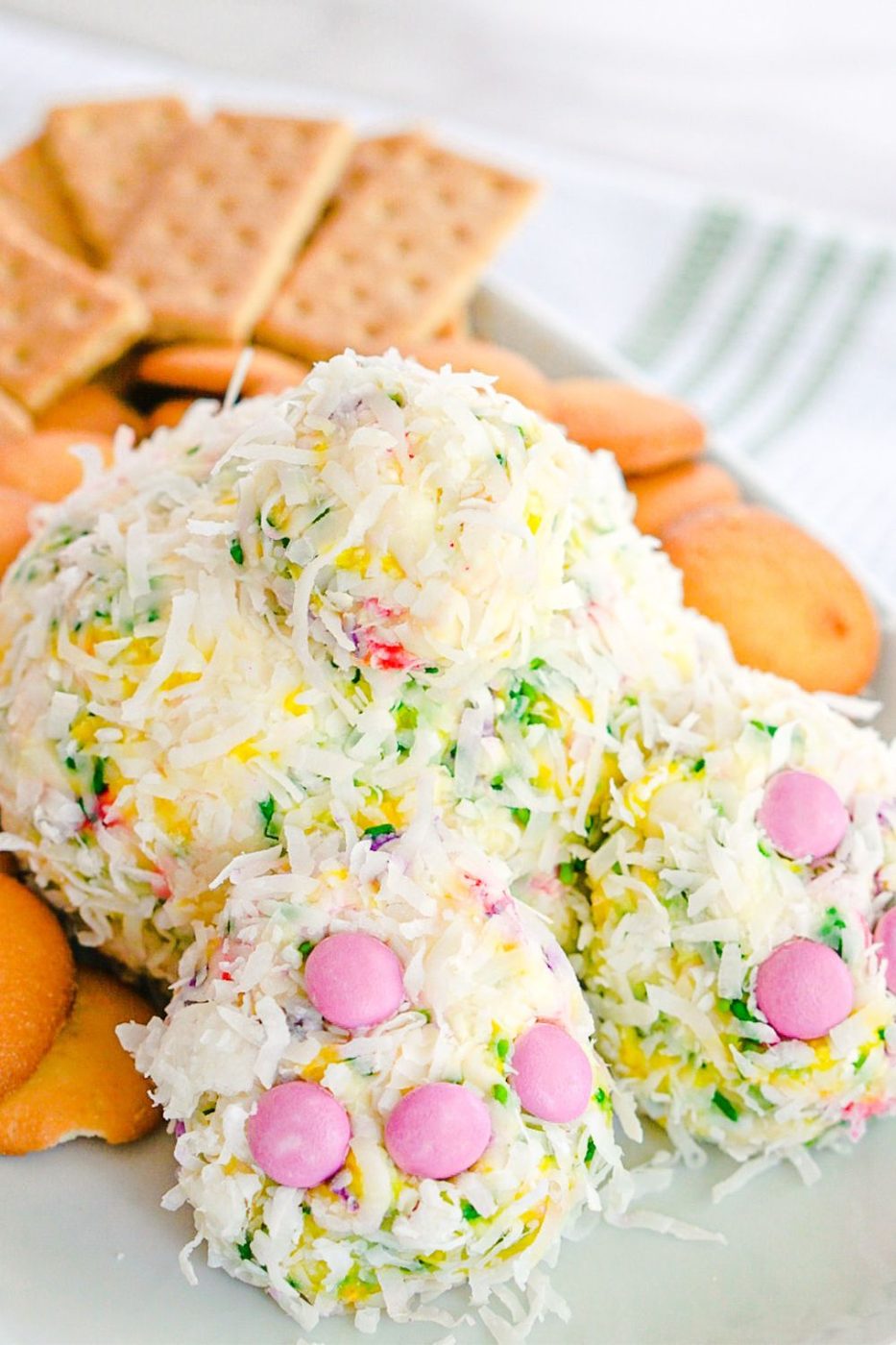 bunny butt cheeseball on a white serving tray with graham crackers and cookies around it 