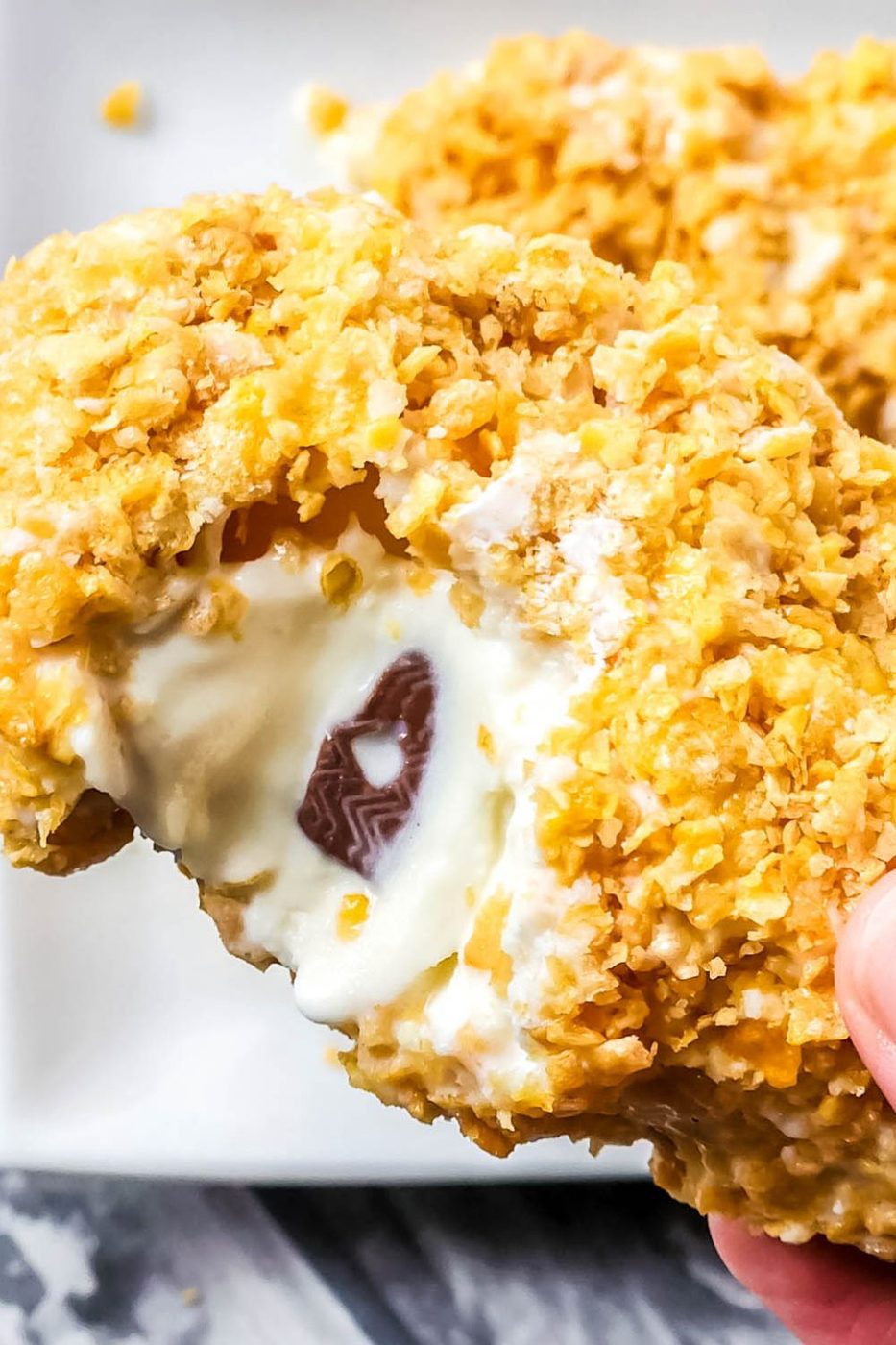 bitten taken out of fried chicken ice cream bar being held in hand 