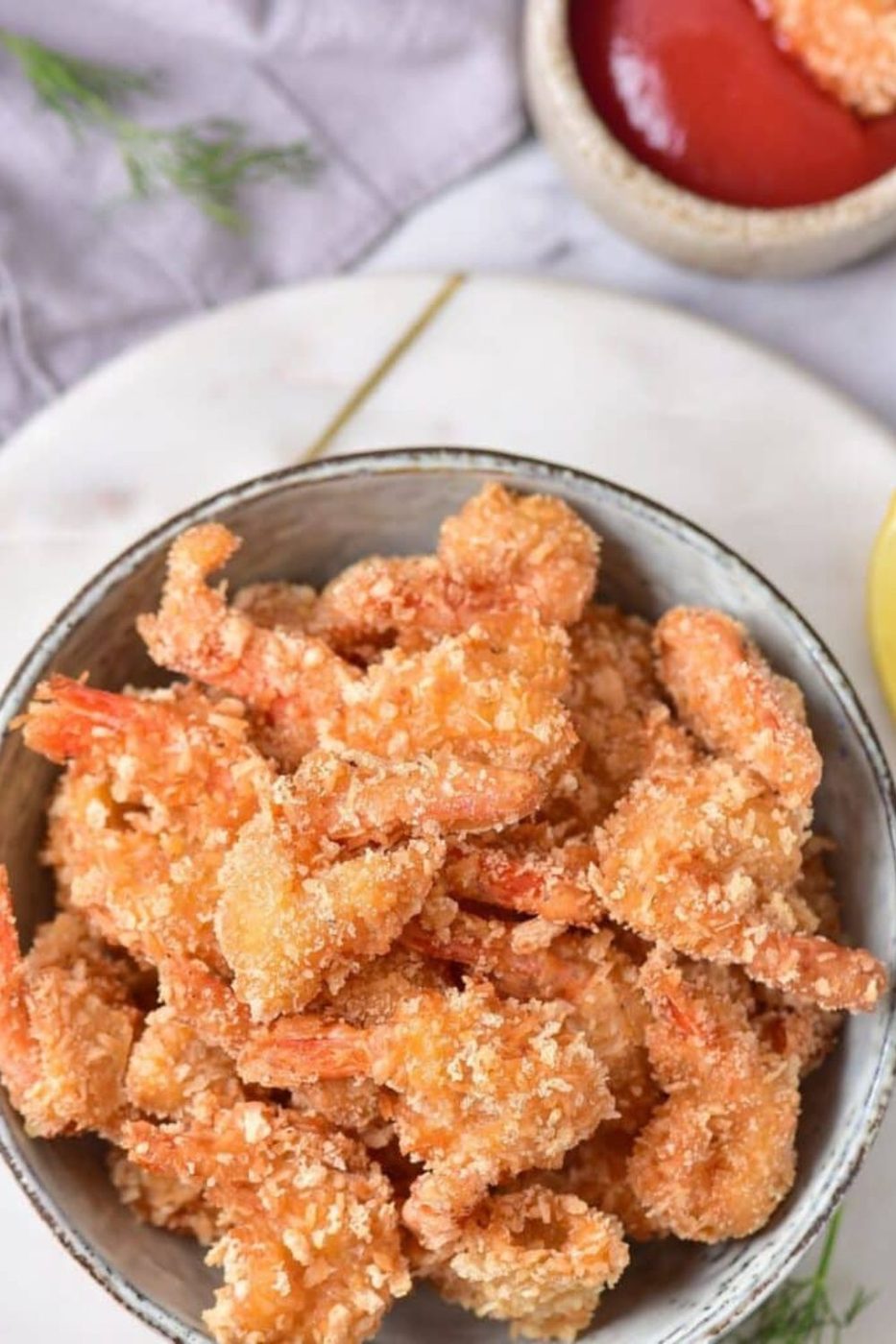 Fried Coconut Shrimp in a bowl with some dipping sauce to the side 