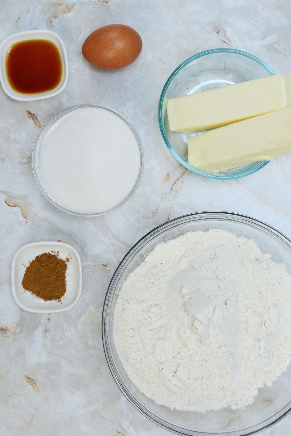 ingredients to make sugar cookies on table in glass bowls