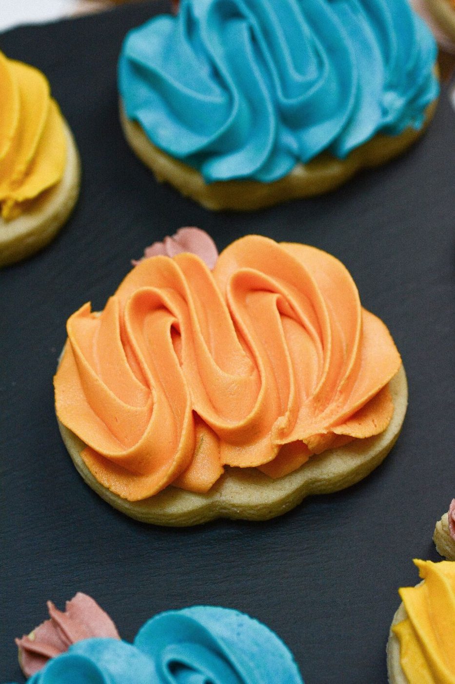 pumpkin shaped cookies with frosting on top of them on black table