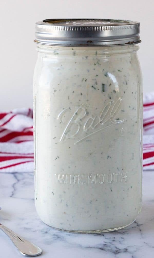 homemade salad dressing in a mason jar on marble table 