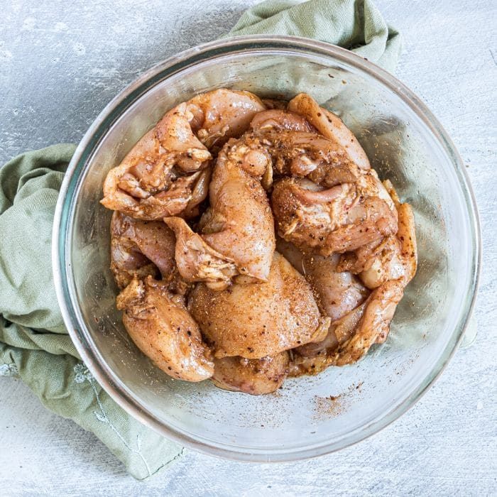 raw chicken in a bowl with seasoning