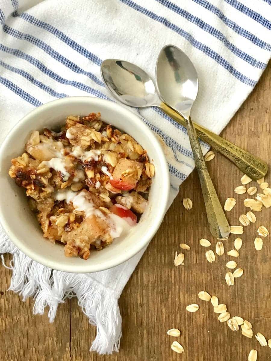apple crisp on table with two spoons sitting by it. 