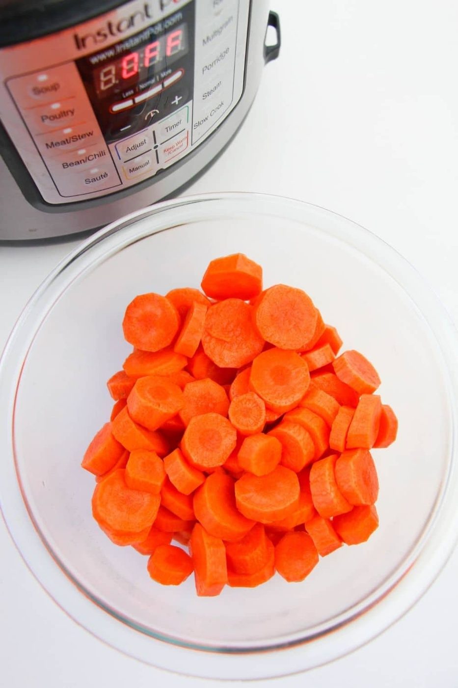 sliced carrots in a bowl with Instant Pot behind it