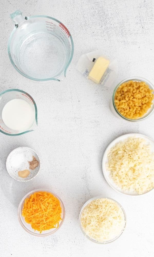 all the ingredients for macaroni and cheese on marble counter in bowls 