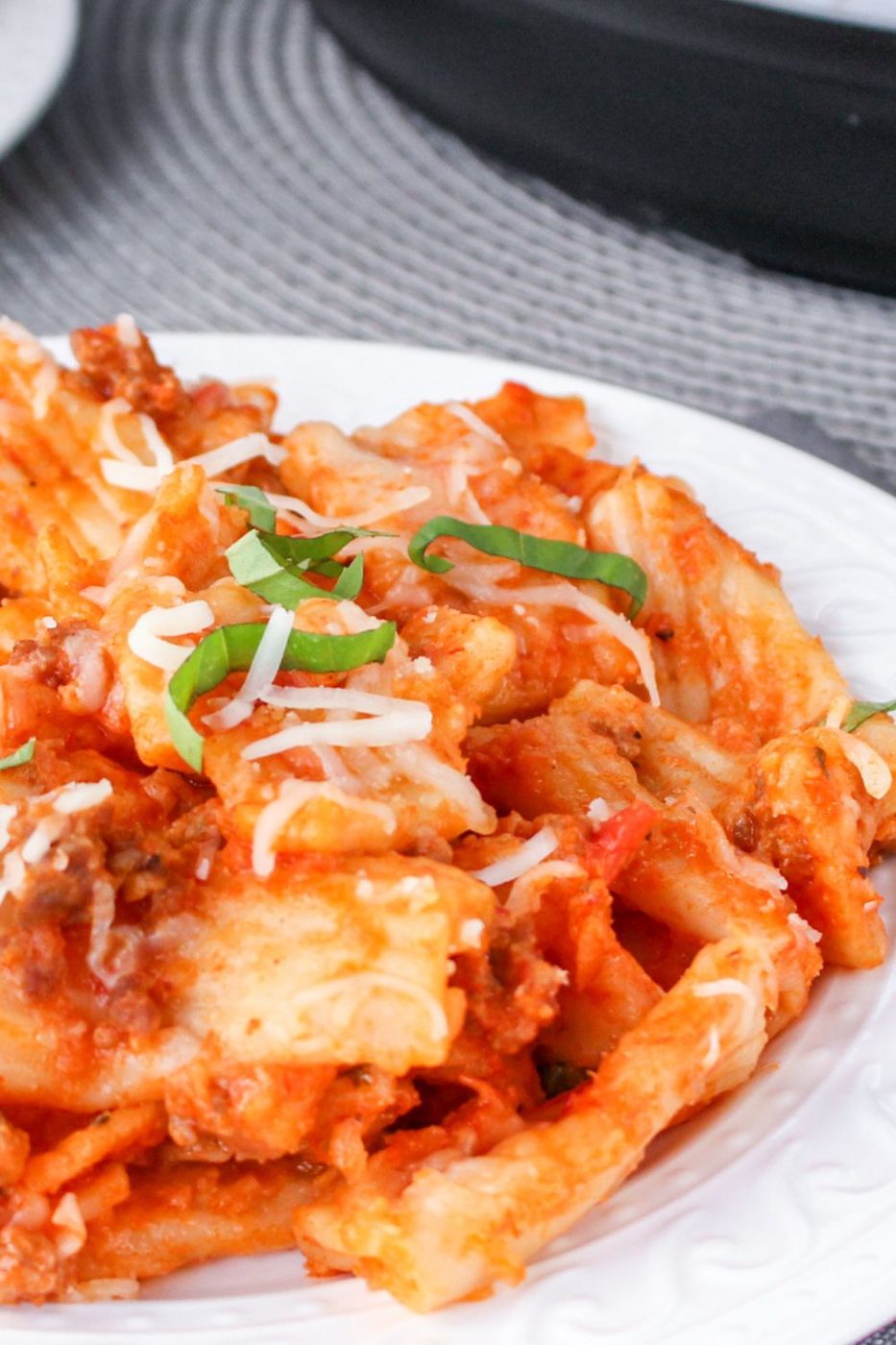 plate with pasta on it topped with basil and marinara sauce