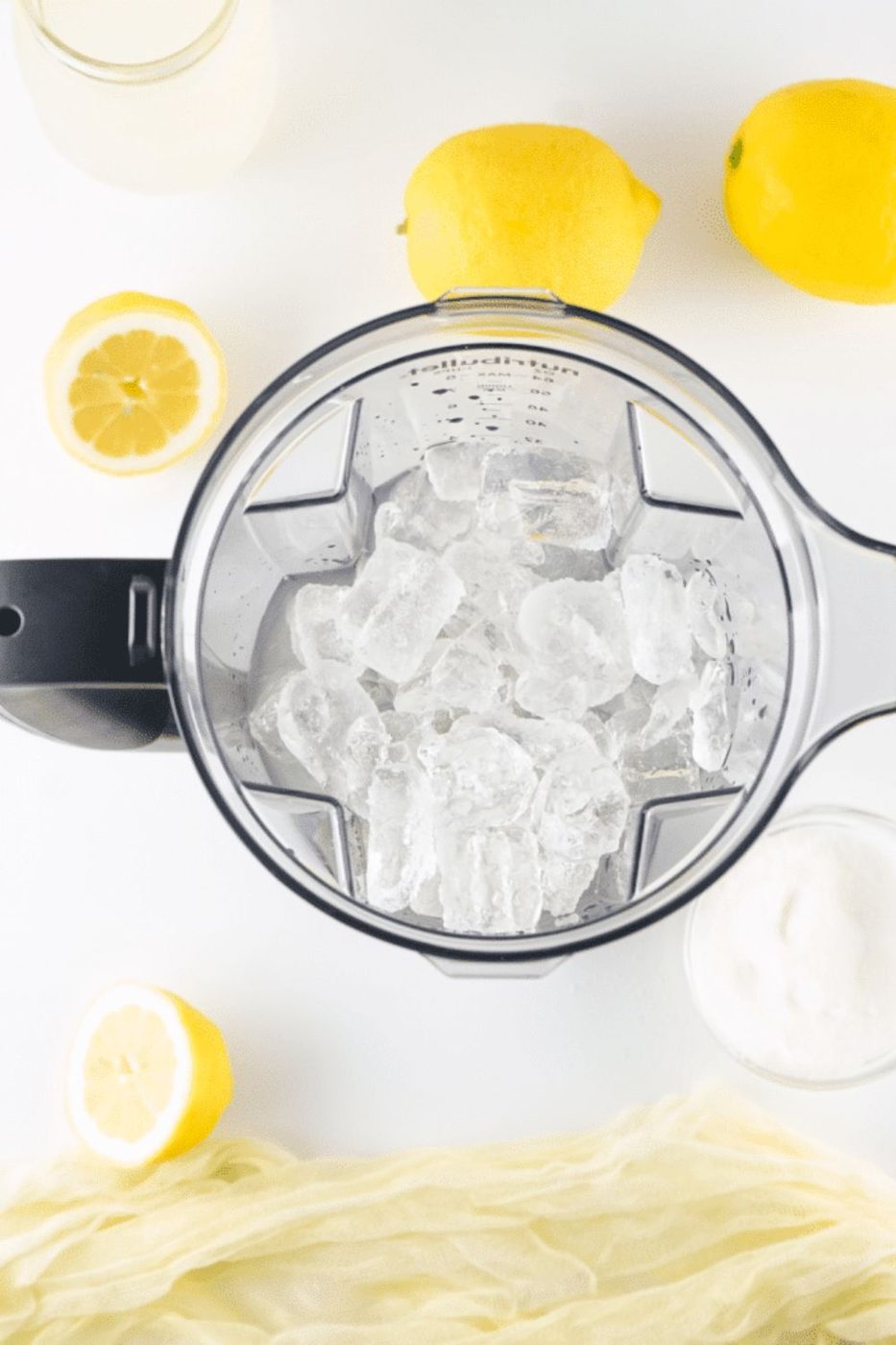 ice in a blender on table with lemons on table 