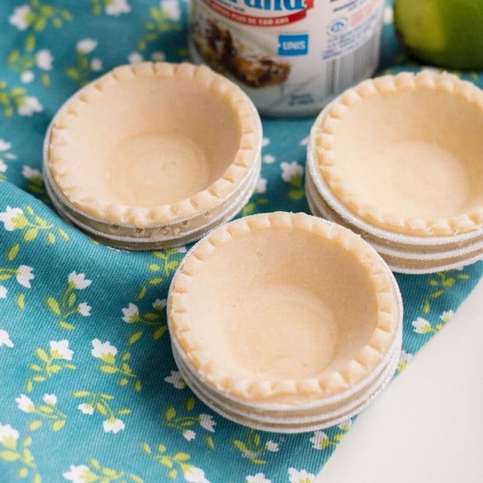 small tartlet crusts stacked on a table with floral towel