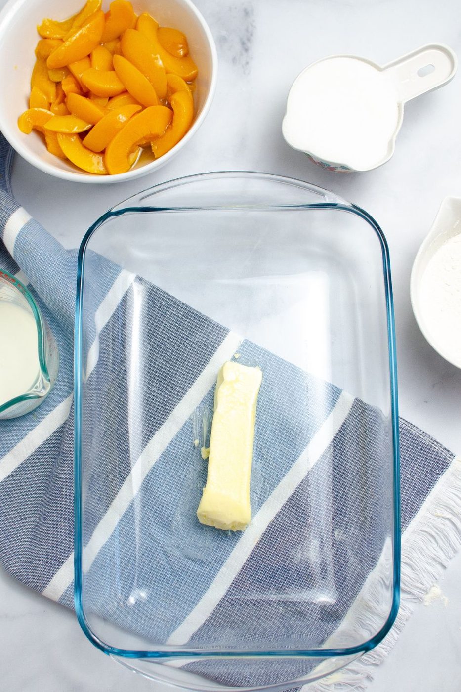 stick of butter in a 9x13 baking dish sitting on table 