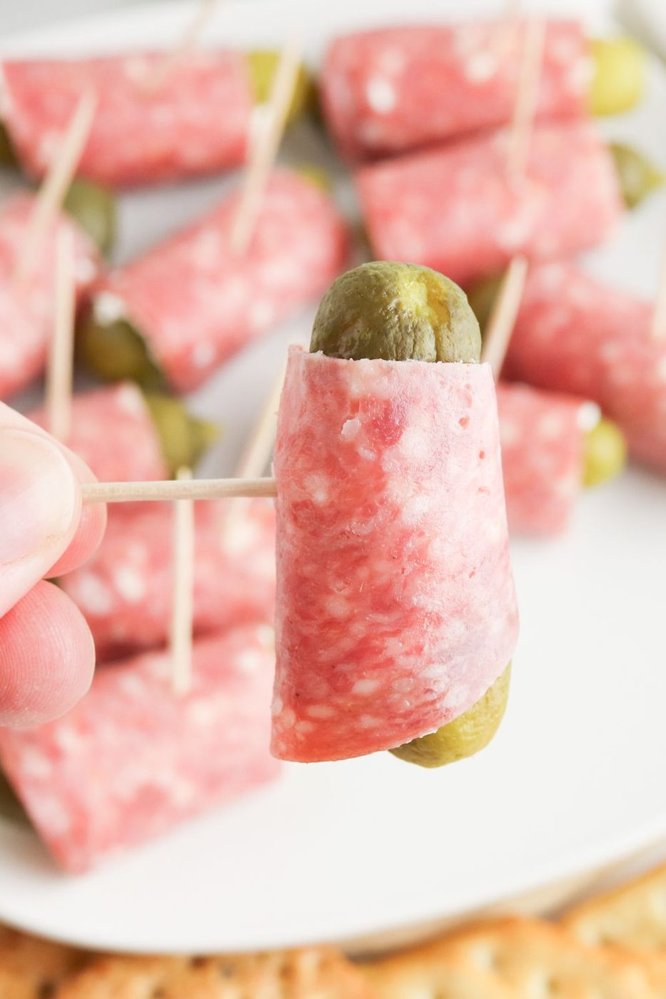dill pickle pinwheels on plate and a wrap on a toothpick in hand 