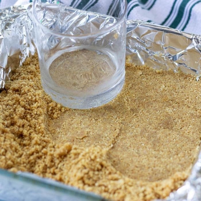 packing graham cracker crust down with a glass cup 